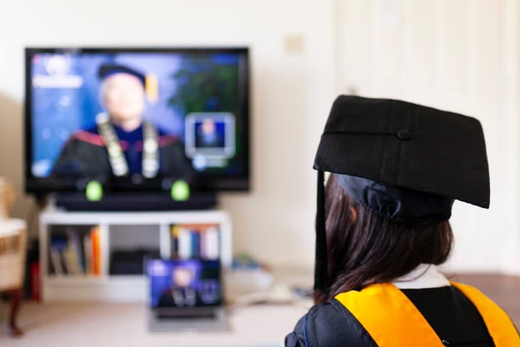 A graduate watches a convocation ceremony online.